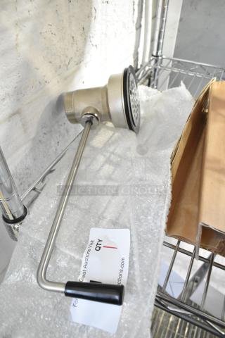 New Regency sink drain, scratch and dent condition, stainless steel, includes handle, auction tag present.