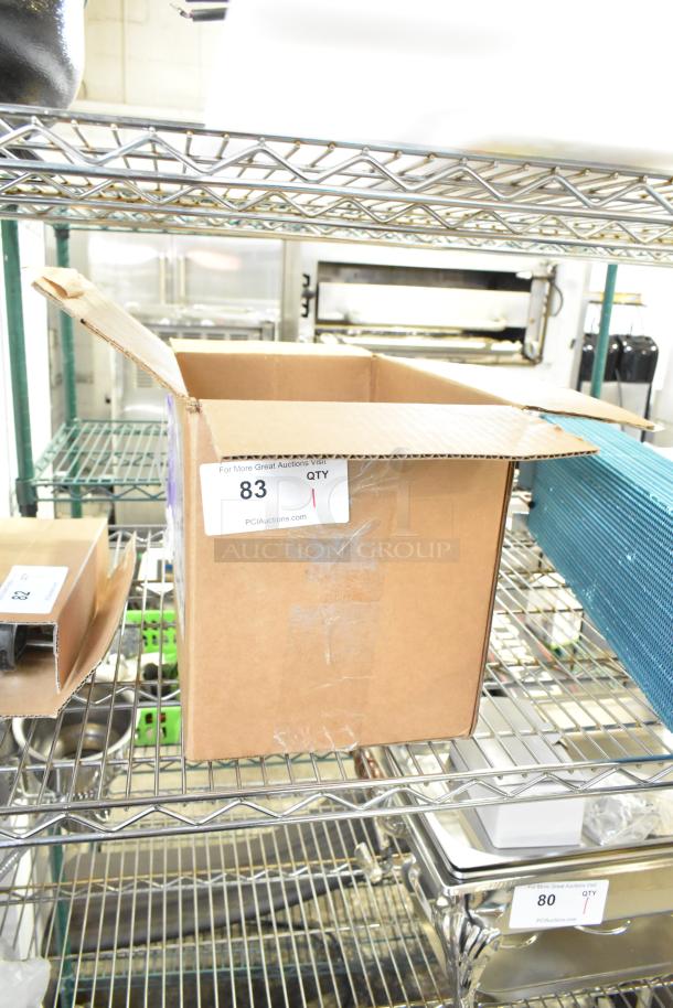 Cardboard box with opening flaps on a metal shelf, labeled with auction number 83. Contains a brand new scratch and dent pump assembly, 115 volts, 1 phase.