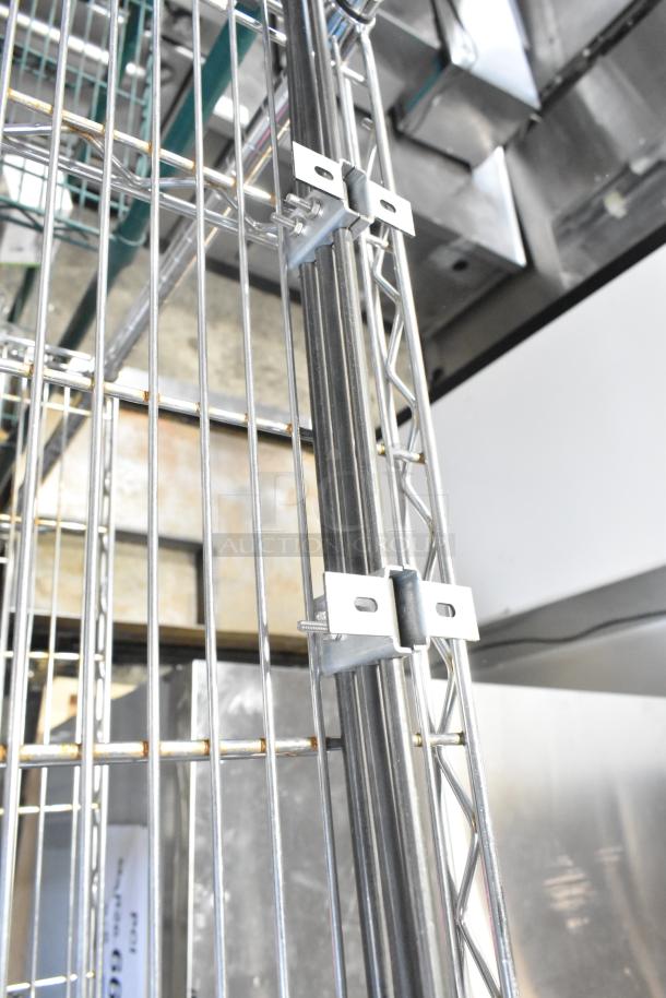 Steel wire shelving with brackets, brand new but with visible scratches and dents, showing industrial background.