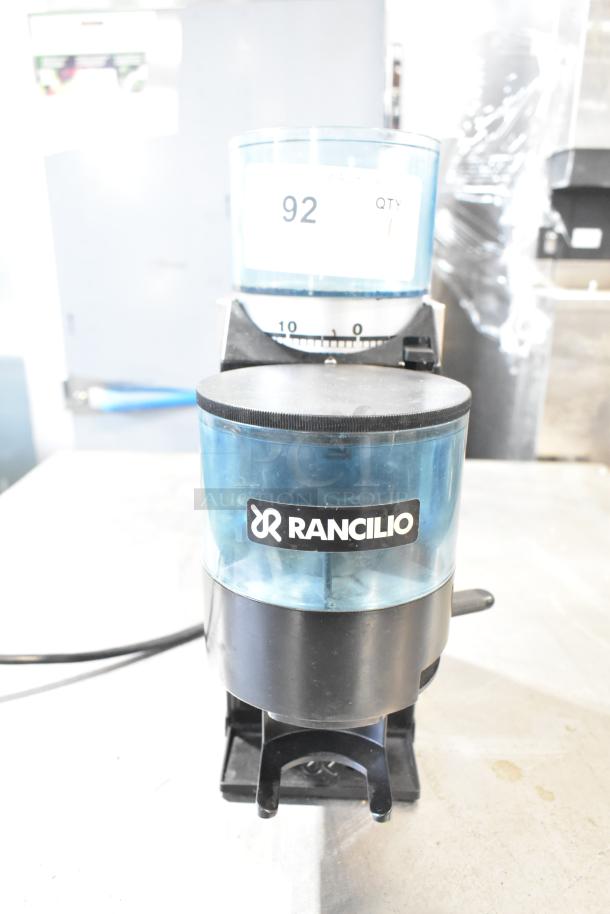 Rancilio Rocky Doser espresso bean grinder, no lid, 110V. Black body, clear hopper, branded logo. Good condition.
