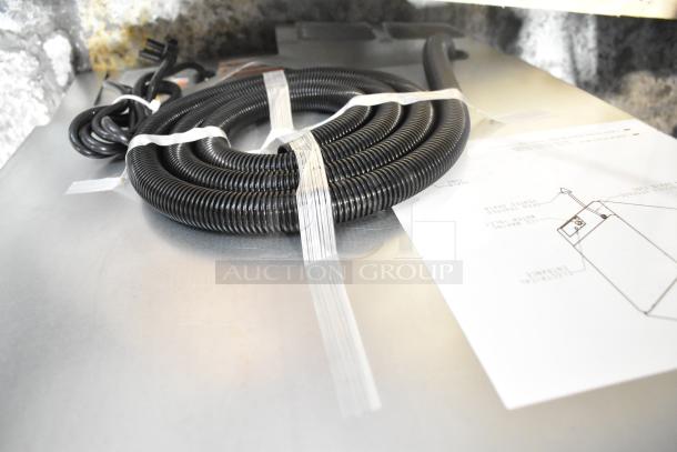 Coiled black tubing and instruction diagram for the Manitowoc UDP0065A-161 ice machine, shown on a metallic surface.