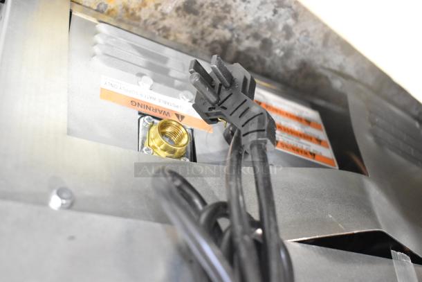 Alt text: Manitowoc UDP0065A-161 ice machine connection showing power cord, brass fitting, and warning labels.