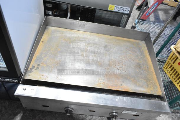 US Range commercial countertop gas griddle with signs of rust and wear, three control knobs, and sturdy metal construction.