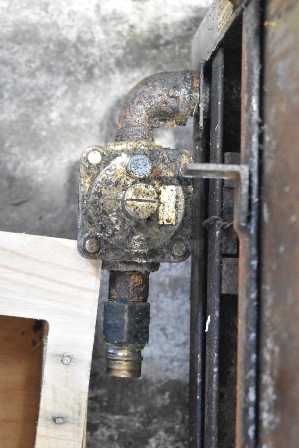 Close-up of a rusted gas valve on a US Range commercial countertop gas-powered flat top griddle. Condition shows wear.