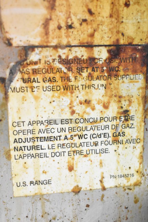 US Range commercial gas flat top griddle label, showing regulator settings and natural gas usage instructions. Rust visible.