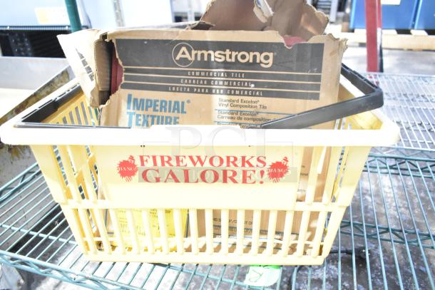 Yellow basket with "FIREWORKS GALORE!" label, containing Armstrong tile box and assorted items. Condition varies.