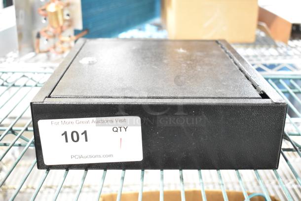 Black metal box with textured finish, labeled "101" by PCI Auctions, in used condition and resting on a wire shelf.