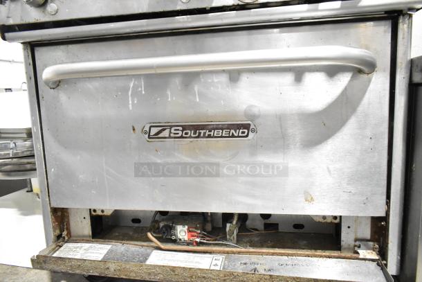Southbend commercial natural gas 6-burner range with oven, cheese melter, back splash, visible wear, Southbend logo.