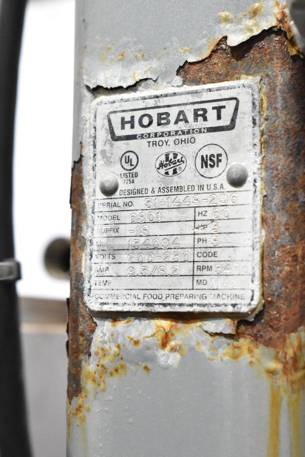 Hobart 6801 commercial meat saw label displaying model, voltage (200-230V), phase (3), and serial number. Rust visible, indicating wear.