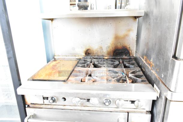 Imperial commercial gas range with 4 burners, flat top griddle, oven, over shelf, and back splash on casters. Used condition.