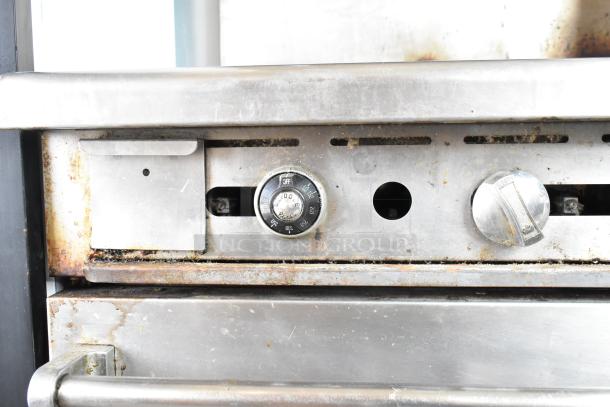 Imperial commercial gas range, 4 burners, flat top griddle, oven, over shelf, back splash, commercial casters, shown with wear.