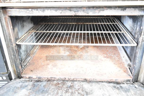 Imperial gas 4-burner range with flat top griddle, oven, overshelf, backsplash, on commercial casters; visible rust and wear.