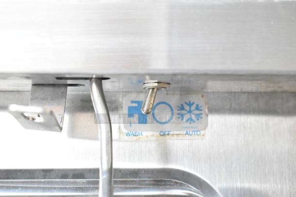 Taylor frozen beverage machine switch showing wash, off, and auto settings. Stainless steel casing visible.