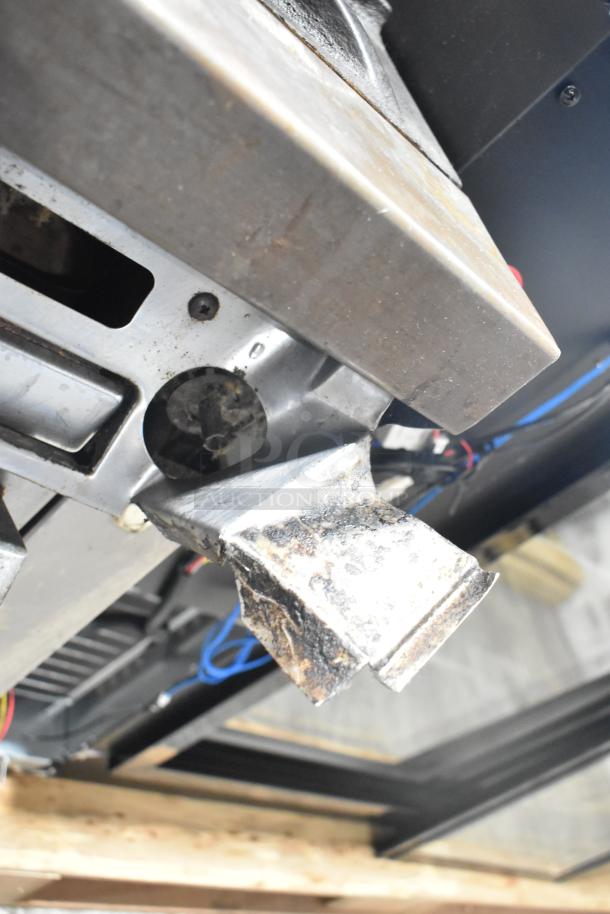 Garland commercial gas-powered 4 burner range with oven, over shelf, and back splash, showing underside components.