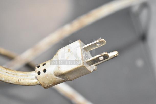 Close-up of a plug with visible wear, connecting Montague commercial gas-powered convection oven with view-through doors.