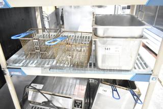 Two fryer drop-in bins and two fry baskets on a shelf. Bins with labels "141 QTY 4." Baskets have blue handles.