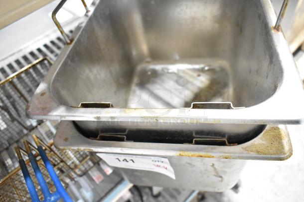 4 kitchen items including 2 fryer drop-in bins and 2 fry baskets. Used condition with visible wear and number tag "141".