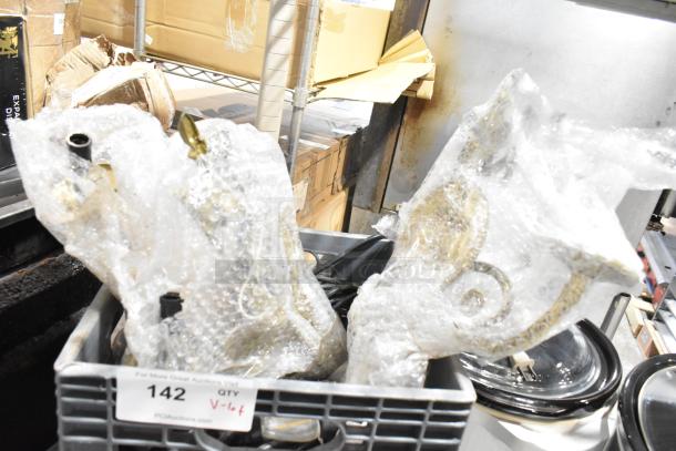 A variety of items in a crate, including a light string and light fixture, partially wrapped in bubble wrap, marked "Lot 142."