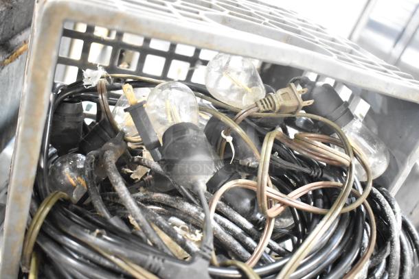 Lot of various items including tangled light string and light bulbs in a metal crate, showing wear and dust accumulation.