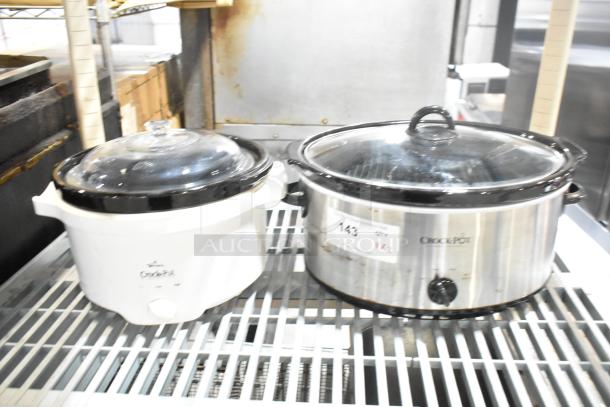 Two slow cookers: Rival 3950 (white) and Crock Pot SCV803-SS (stainless steel). Both feature glass lids, 120V, 1 phase. Good condition.