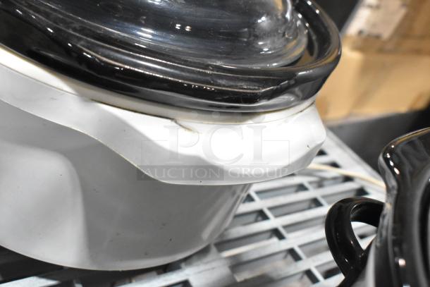 Two slow cookers, including Rival 3950 and Crock Pot SCV803-SS, 120V, with black and white lids, on a metal rack.