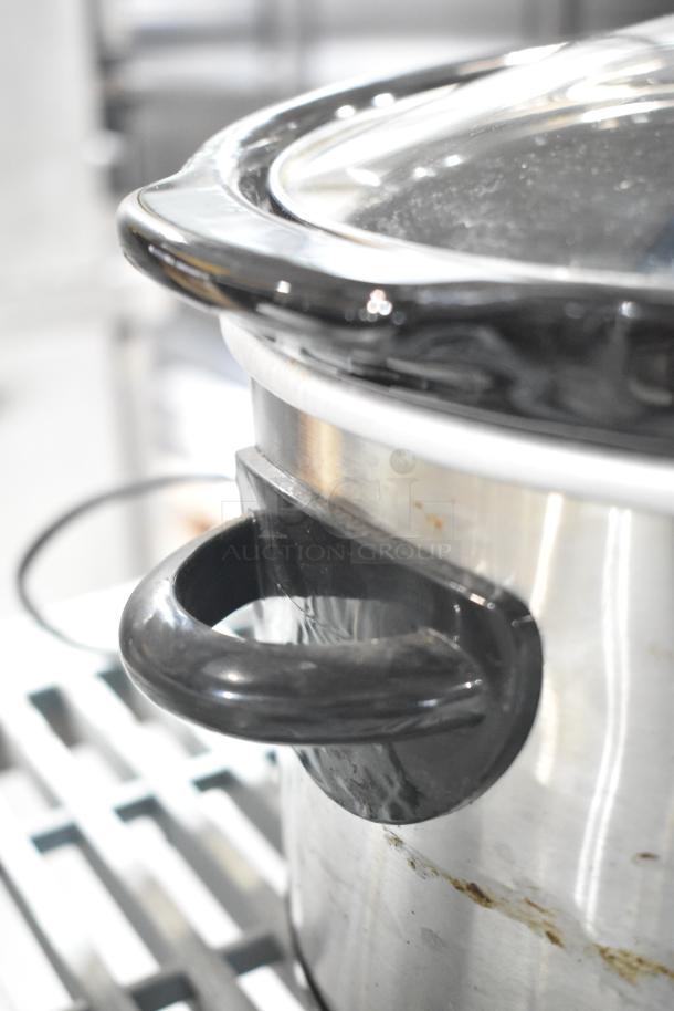 Two slow cookers, including Rival 3950 and Crock Pot SCV803-SS. Stainless steel, black handles, visible wear. 120V, 1 phase.