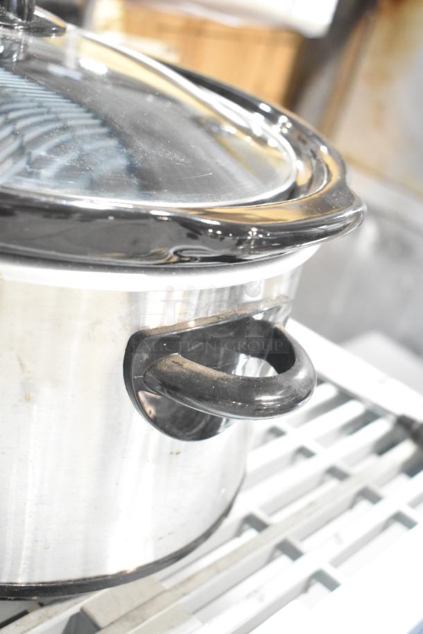 Rival 3950 Slow Cooker, stainless steel, visible wear, black handle, glass lid. Auction includes Crock Pot SCV803-SS.