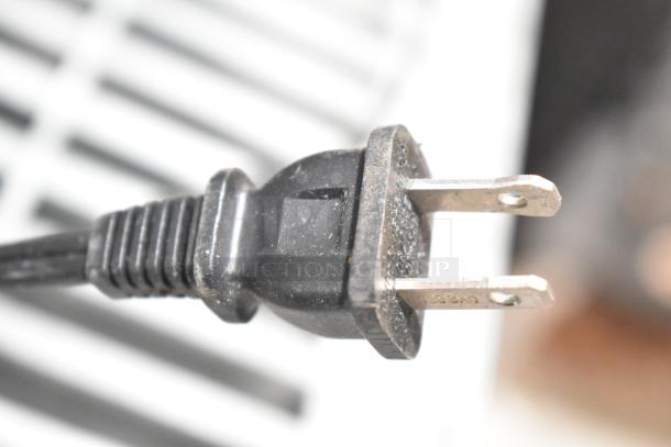 Close-up image of a black, two-prong power plug for a slow cooker, slightly dusty, indicating regular use.