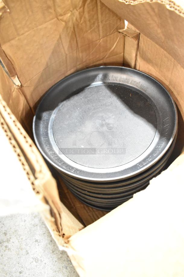 Box containing several Aladdin Temp-Rite black poly trays, stacked, showing surface wear and care instructions.