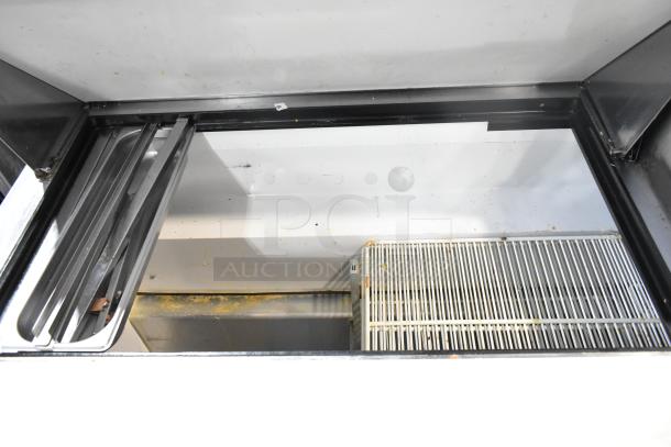 True TSSU-72-30M-B-ST prep table interior view, commercial-grade, with sliding lids, shelves, visible wear.