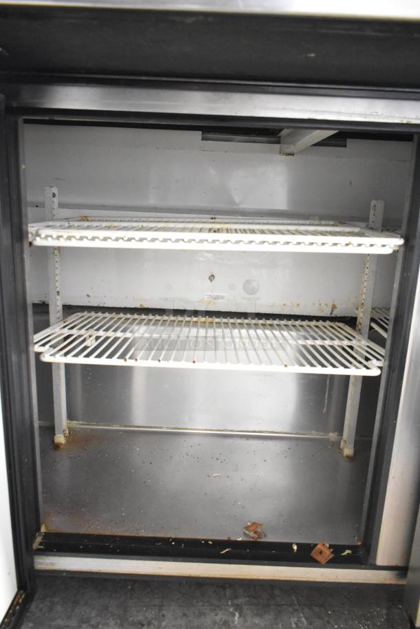 True TSSU-72-30M-B-ST prep table with commercial casters, stainless steel interior, showing empty, two-tiered wire shelving.