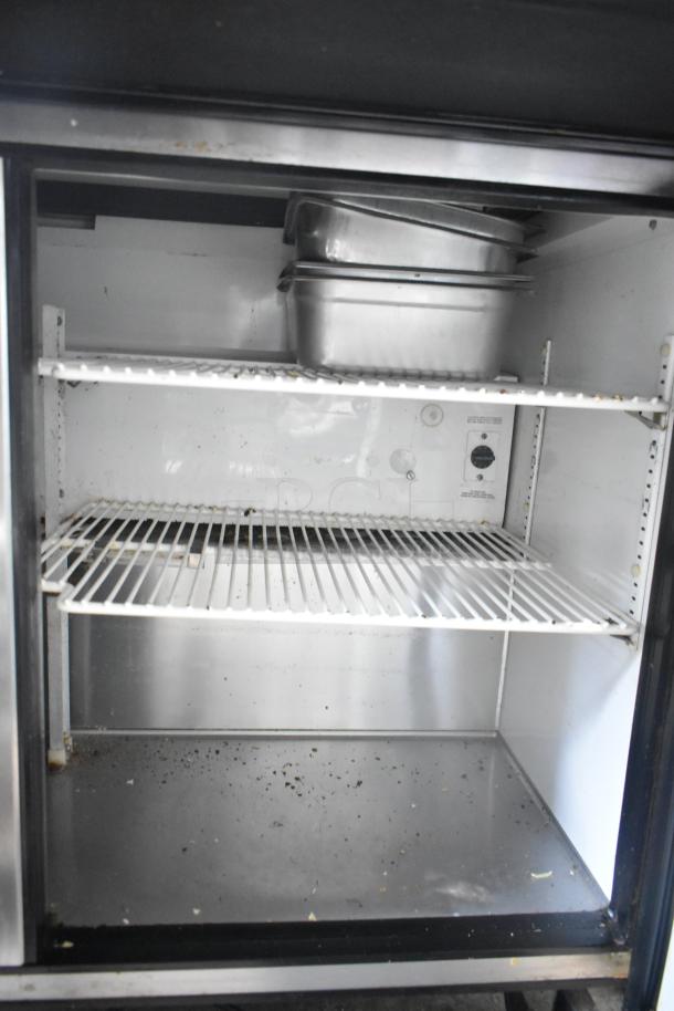 True TSSU-72-30M-B-ST commercial sandwich salad prep table interior with pans on shelf; used condition.