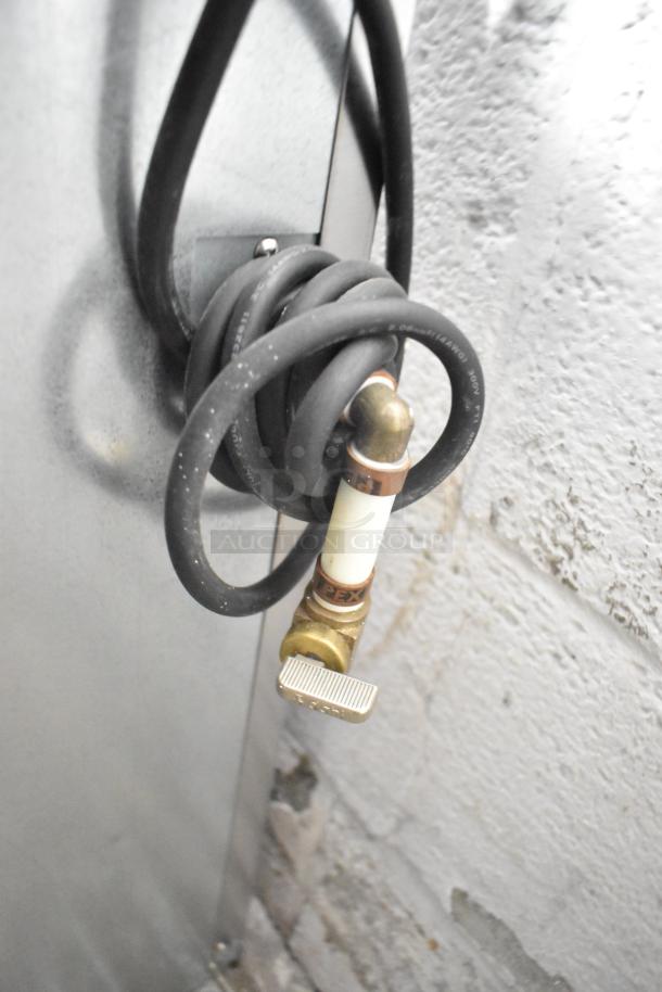 Coiled hose with brass connector attached to a wall; part of Hoshizaki DCM-300BAH Icemaker installation.