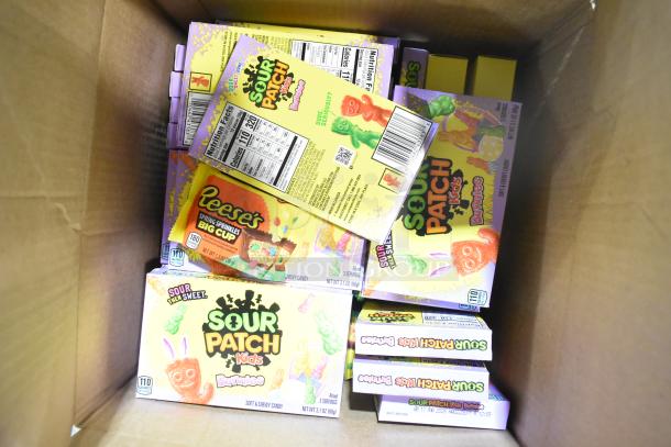 Box of assorted candy including Sour Patch Kids, Sweet Tarts, Reese's, and more. Multiple boxes visible.