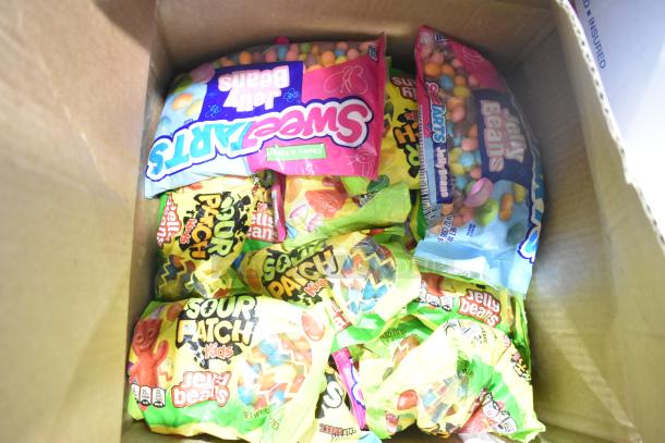 Box of assorted candy including Sour Patch Kids, Sweet Tarts, and jelly beans. Multiple packages visible.