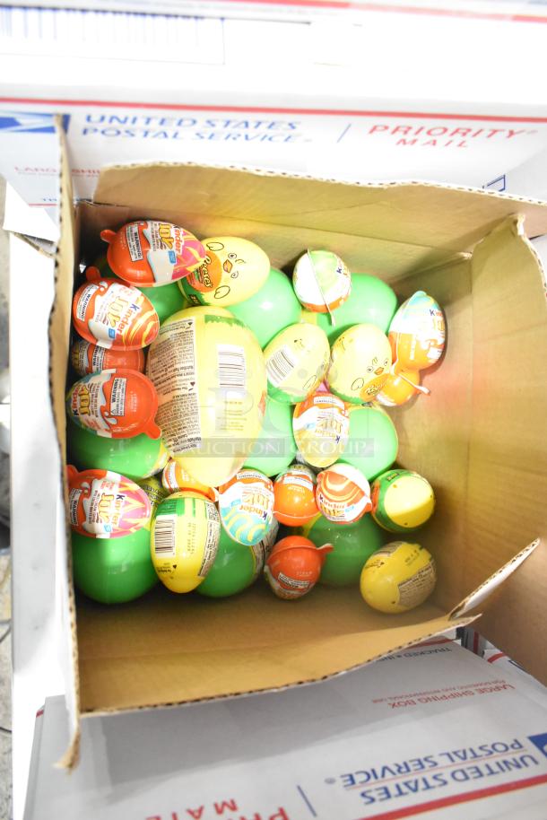 Box of various candies including Kinder Joy eggs and Reese's eggs, in a USPS Priority Mail box.