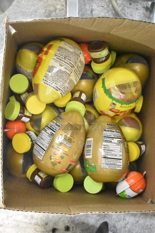 Box filled with assorted candy containers, featuring nutrition labels. Includes various branded sweets.