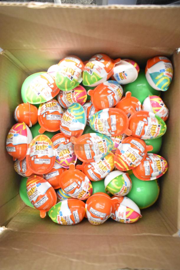 Box filled with Kinder Joy eggs, visible packaging, assorted flavors. Part of a 10-box candy auction lot.