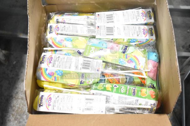 Cardboard box containing various candy packs, including Peeps Rainbow Pop and Reese's. Packages display nutritional info.