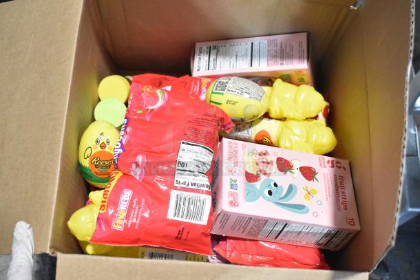 Box containing assorted candies, including Reese's eggs, Starburst FaveREDS, and fruit strip packs, in original packaging.