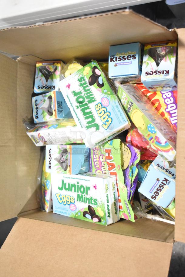 Box containing various candy brands including Junior Mints, Hershey's Kisses, and Sour Patch Kids Bunnies.