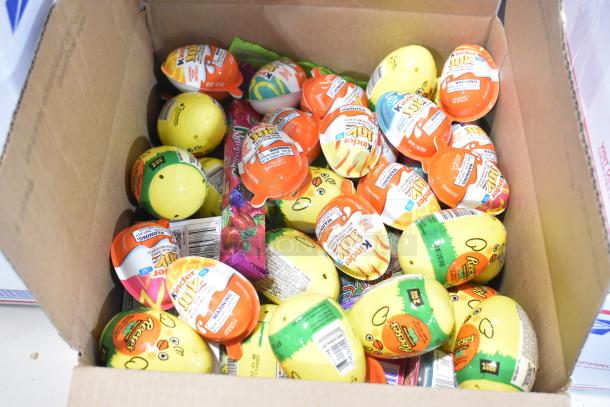 Box containing Kinder Joy eggs, Reese's eggs, and assorted candies. Ideal for collectors or candy lovers.