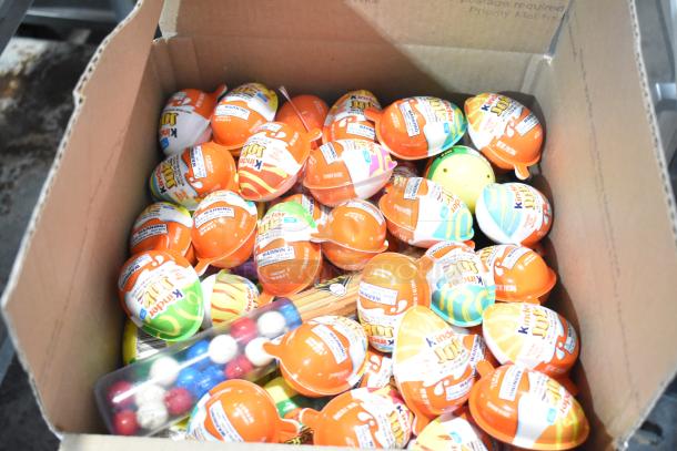 Box of assorted Kinder Joy eggs with colorful packaging, containing small toys and treats.