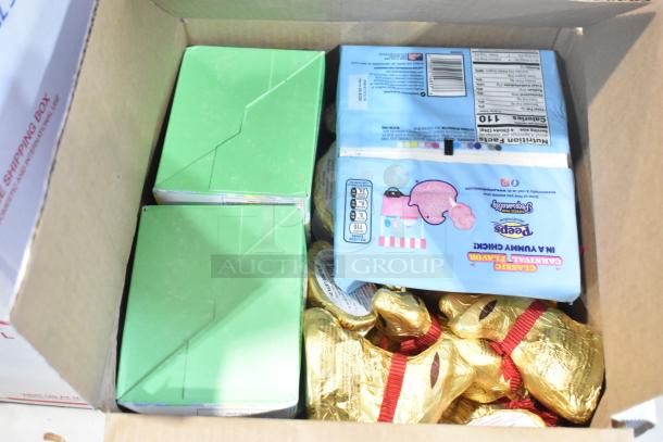 Box containing assorted candy: chocolate bunnies, green-boxed items, Peeps packs, and wrapped treats. Auction lot features variety.