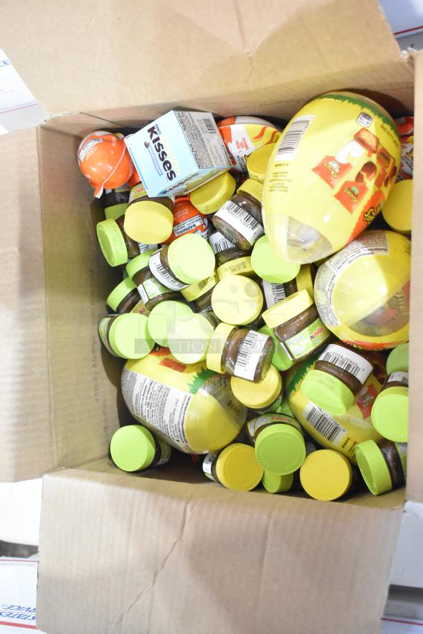 Box filled with assorted candy, including Kinder Joy, Nutella, and exotic sweets. Visible brands and vibrant packaging.