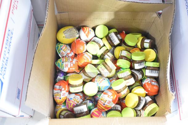 Box of assorted candies including Kinder Joys and Nutella jars, bundled for auction. Mix of chocolate and novelty treats.