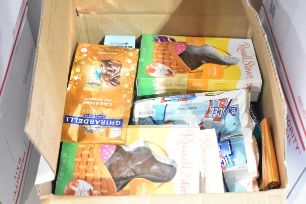 10 boxes of assorted candy including Peeps, Russell Stover chocolate bunnies, Nutella, and Kinder Joys in a cardboard box.