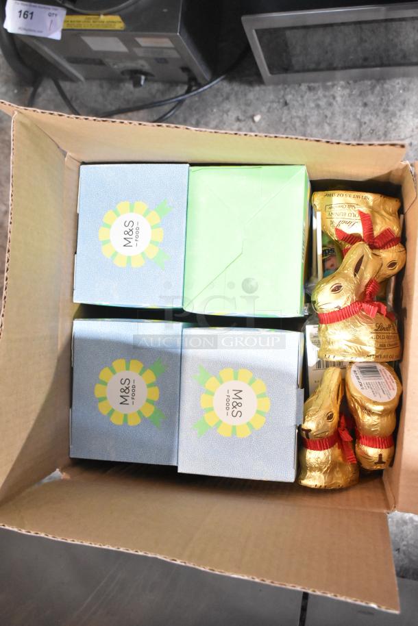 A box containing M&S Food boxes and Lindt gold chocolate bunnies, part of a 10-box candy auction lot.