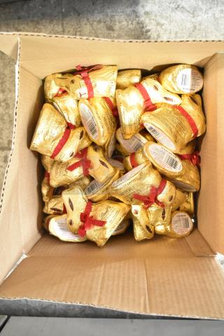 A box filled with Lindt Gold Bunny chocolate figurines, wrapped in gold foil with red ribbons.