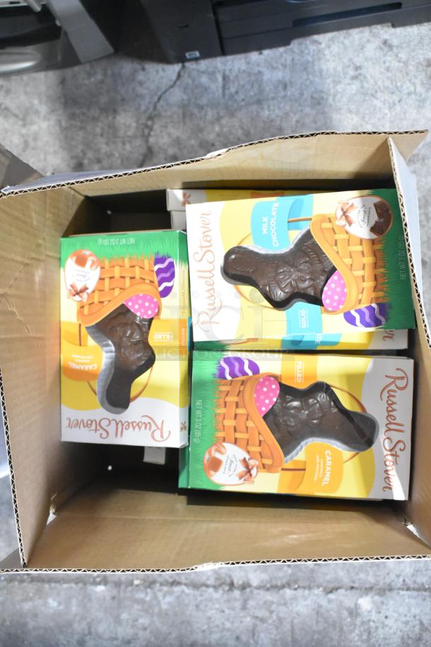 Box containing various candies, including Russell Stover chocolate bunnies. Visible packaging indicates milk chocolate flavor.